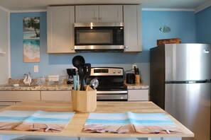 well lit kitchen area complete with island & seatng for 2
