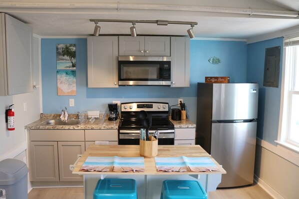 well lit kitchen area complete with island & seatng for 2