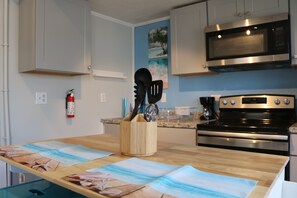 well lit kitchen area complete with island & seatng for 2