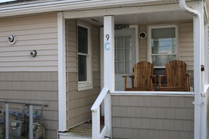 a small porch greets you as you arrive, complete with seating for two on adirondack chairs.