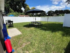 Spacious fenced in backyard with picnic table and bbq grill