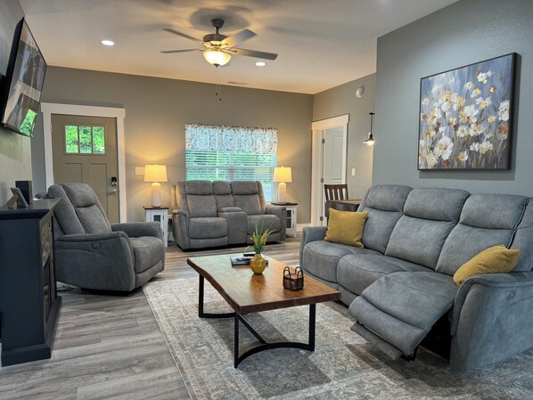 Living room with recliners, electric fireplace, games & game table.