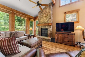 Spacious living area with vaulted ceiling, gas fireplace with stone surround, flat screen TV and access to the back patio.