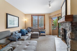 Living area with gas fireplace, mounted flatscreen TV, sleeper sofa and access to the private balcony.