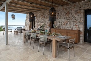 Outdoor dining area framed by a Trani stone wall and pendant light.