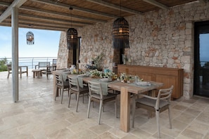 Outdoor dining area framed by a Trani stone wall and pendant light.