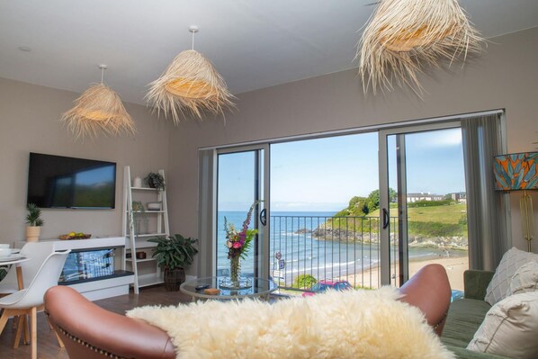 Living area with patio doors and Juliet balcony overlooking the beach and sea