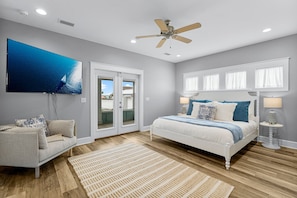 The HUGE primary suite features access to the screened in porch, views of the pool, 65in TV and NEW king bed