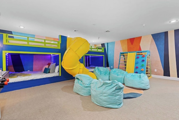 A fun bedroom with 4 queen bunk beds, slide, air hockey and climbing wall and a TV—perfect for relaxing after a day of adventure! | The Juniper, Brian Head, Utah | Voyax Luxury Vacation Rentals
