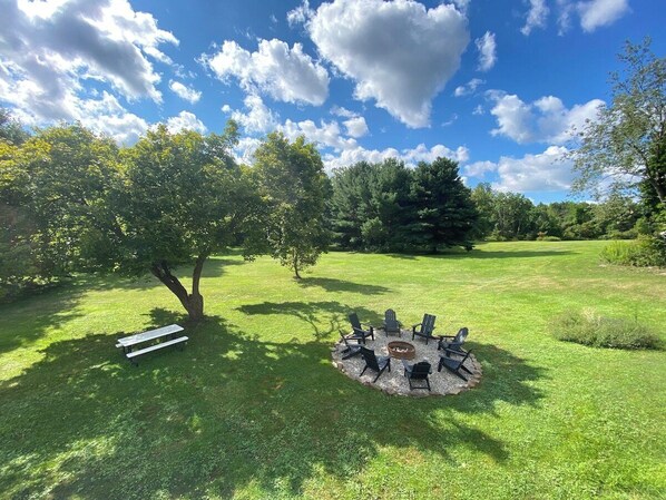 View of the fire pit area and property from the back deck in the summer time. 