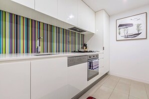 A colourful splashback brightens up the streamlined kitchen, where you’ll find all you need to cook some fresh produce from nearby Prahran Market and a dishwasher for easy clean-up. 
