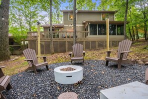 Embrace the warmth of our open firepit as you take in the enchanting view of the house nestled among the trees