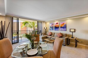 Enjoy meals at this elegant glass dining table with plush seating and a tropical view, just steps from the balcony overlooking the resort's lush gardens and the Pacific Ocean.