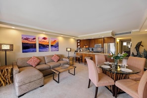 Relax in this stylish living room featuring a large sectional sofa, vibrant sunset artwork, and unique decor elements, creating the perfect retreat after a day in Maui.