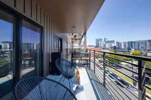 Unit 2: Balcony / Patio accessible through the living room and primary bedroom featuring outdoor furnishings for dining and lounging accompanied with city views.