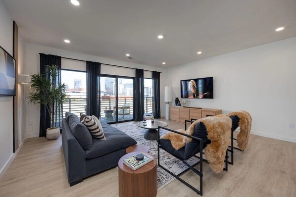 Unit 1: Spacious living room with wilderness-inspired decor featuring smart TV, comfortable seating, and private patio.