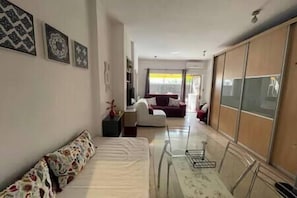 Modern and cozy studio with a single bed, dining area, living area with sofa bed, TV, and a balcony. (1)