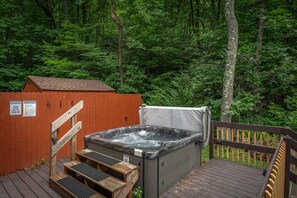 Hot tub on the side porch surrounded by nature.