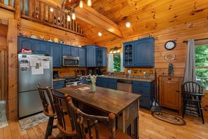 Sleek kitchen with island seating, high chair, dishwasher, and 2 types of coffeemakers (Keurig and drip-style).