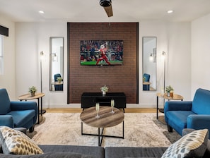 Warm and inviting living room featuring a Smart TV for entertainment, and designer furnishings including a sleeper sofa that converts into a Queen Bed.