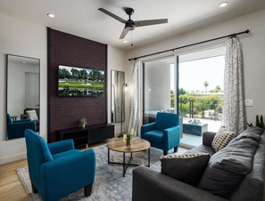 1st Floor: Warm and inviting living room featuring a Smart TV for entertainment, and designer furnishings including a sleeper sofa that converts into a Queen Bed.