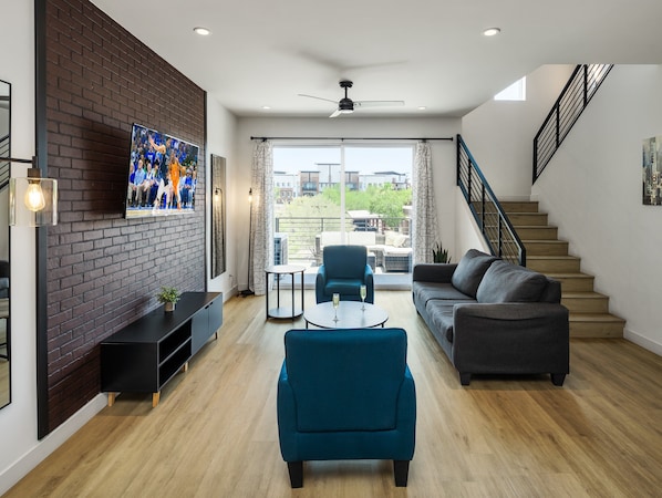 1st Floor: Warm and inviting living room featuring a Smart TV for entertainment, and designer furnishings including a sleeper sofa that converts into a Queen Bed.