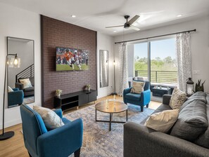 1st Floor: Warm and inviting living room featuring a Smart TV for entertainment, and designer furnishings including a sleeper sofa that converts into a Queen Bed.