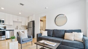 Bright living room with comfortable seating, smart tv, and queen sleeper with bedding