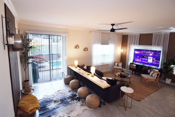 Stylish open-plan living space with sofas, Smart TV, fan, doors to the pool deck