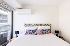 The light and airy bedroom features a queen-size bed with side tables and reading lamps, as well as mirrored built-ins, direct balcony access and split-system heating and cooling. 