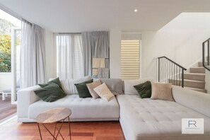 Living room with large luxurious couch and doors opening to outdoor lounge area