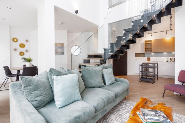 Spacious open-plan living room and fully equipped kitchen area with a dining table, offering access to a private, furnished patio.