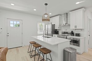 Welcome to your dream kitchen, where modern elegance meets functionality. This bright and airy space features stunning white cabinetry, sleek stainless steel appliances, and a spacious island perfect for meal prep and casual dining. Large windows flo