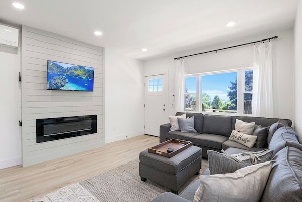 Enjoy ultimate relaxation in this contemporary living room, designed with your comfort in mind. The mounted TV and electric fireplace create a cozy atmosphere for movie nights or quiet evenings. Large windows and modern décor make this the perfect sp