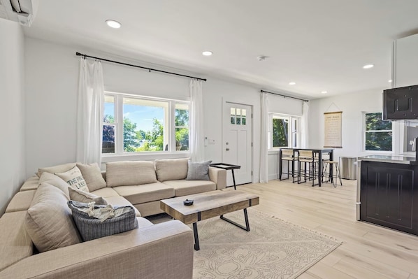 Bask in the natural light that floods this elegant living area. The spacious sectional sofa and minimalist décor provide a tranquil setting for relaxation. With large windows and a serene color palette, this living room offers a perfect retreat for u