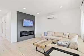 Unwind in this beautifully designed living room featuring a modern fireplace and a comfortable sectional sofa. The neutral tones and contemporary décor create a relaxing and inviting atmosphere, perfect for cozy nights in. Enjoy your favorite shows o