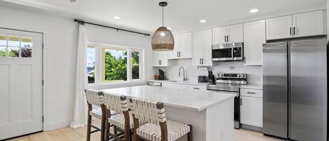 This open-concept kitchen and living area offer the perfect blend of modern elegance and cozy comfort. The kitchen's island provides ample seating and counter space, ideal for entertaining or family meals. The seamless flow into the living room ensur