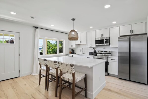 This open-concept kitchen and living area offer the perfect blend of modern elegance and cozy comfort. The kitchen's island provides ample seating and counter space, ideal for entertaining or family meals. The seamless flow into the living room ensur