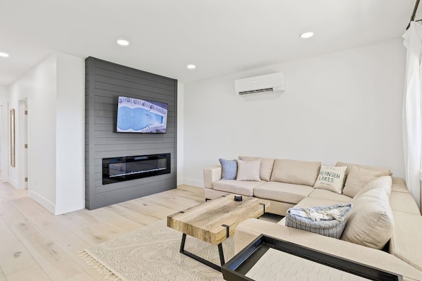 Unwind in this beautifully designed living room featuring a modern fireplace and a comfortable sectional sofa. The neutral tones and contemporary décor create a relaxing and inviting atmosphere, perfect for cozy nights in. Enjoy your favorite shows o
