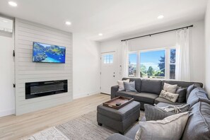 Enjoy ultimate relaxation in this contemporary living room, designed with your comfort in mind. The mounted TV and electric fireplace create a cozy atmosphere for movie nights or quiet evenings. Large windows and modern décor make this the perfect sp