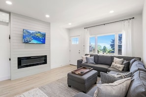 Enjoy ultimate relaxation in this contemporary living room, designed with your comfort in mind. The mounted TV and electric fireplace create a cozy atmosphere for movie nights or quiet evenings. Large windows and modern décor make this the perfect sp