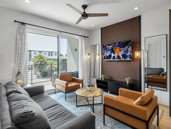 Unit 1 (1st Floor): Warm and inviting living room featuring a Smart TV for entertainment, and designer furnishings including a sleeper sofa that converts into a Queen Bed.