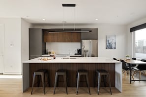 Unit 5 - 1st Floor: Fully equipped modern kitchen featuring culinary essentials, stainless steel appliances, island bar seating, and a dining area.