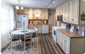Kitchen area has a larger kitchen with a rectangular table, a bench a, 4chairs