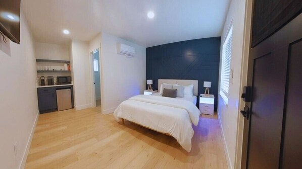 Unwind in style on the spacious queen-sized bed, complemented by a stunning accent wall that adds a touch of character to the room. The crisp, white linens create a peaceful ambiance, while the side tables feature mood lighting, wireless chargers, and USB