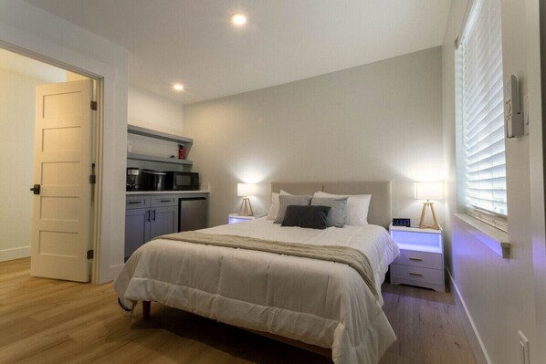 Unwind in comfort on the spacious queen-sized bed, with crisp white linens that create a peaceful ambiance. The side tables are equipped with mood lighting, wireless chargers, and USB ports, adding convenience and relaxation to your stay.