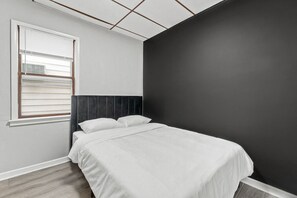 Chic bedroom with a bold black accent wall and soft bedding—perfect for a peaceful stay.
