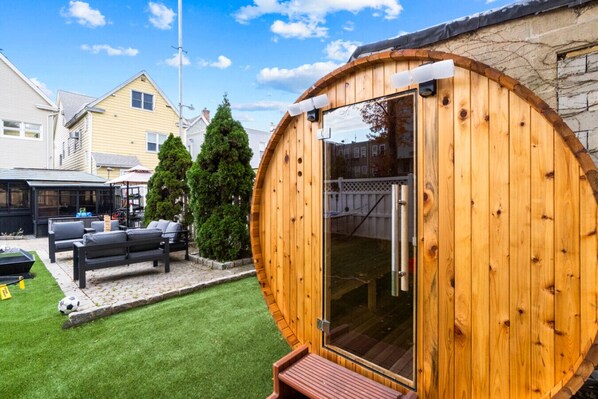 Escape to a tranquil backyard retreat with a wooden sauna and lush green space, ideal for a refreshing break.