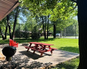 Patio, fire pit and grill facing the yard and tennis court