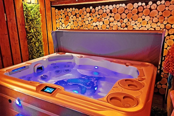 Der überdachte Whirlpool bei Nacht steht in einer halboffenen Scheune